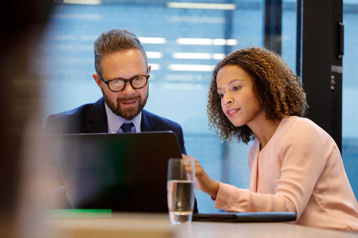 Business man and woman sitting looking at laptop
